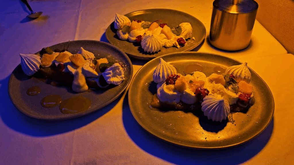 Composition des trois plats servis (burrata, bar rôti, pavlova) présentés sur la table avec vue sur la Seine en arrière-plan